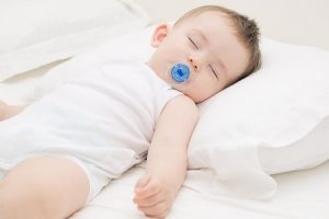 Младенец спит головой на подушке